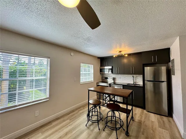 a kitchen with a table chairs refrigerator and window