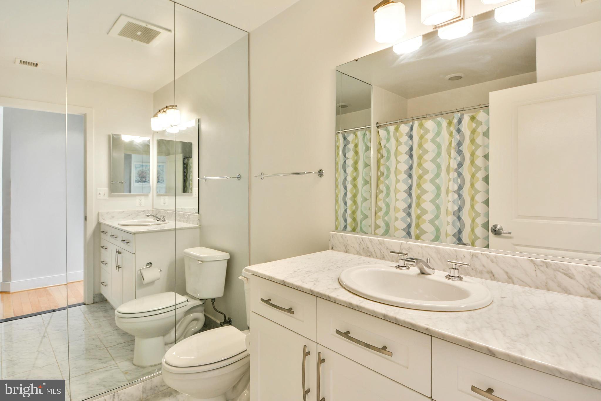 4101 Albemarle Street Northwest, Unit 337 Washington, DC 20016 - Photo 18 of 30 a bathroom with a sink a toilet a mirror and shower