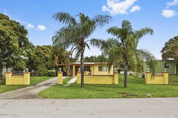a view of a house with a yard and palm trees