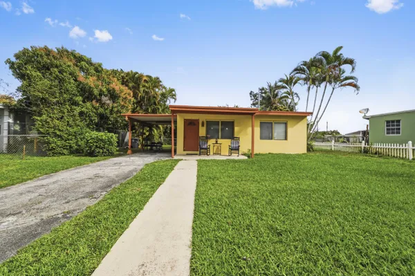 a front view of a house with a yard and potted plants