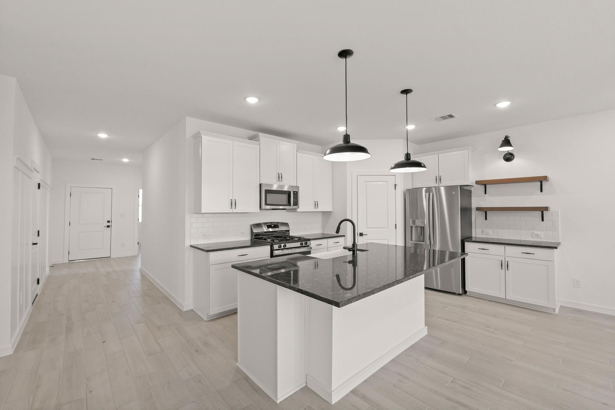 7815 Jade Crest Drive Angleton, TX 77515 - Photo 5 of 31 a kitchen with stainless steel appliances granite countertop a sink a stove and a refrigerator