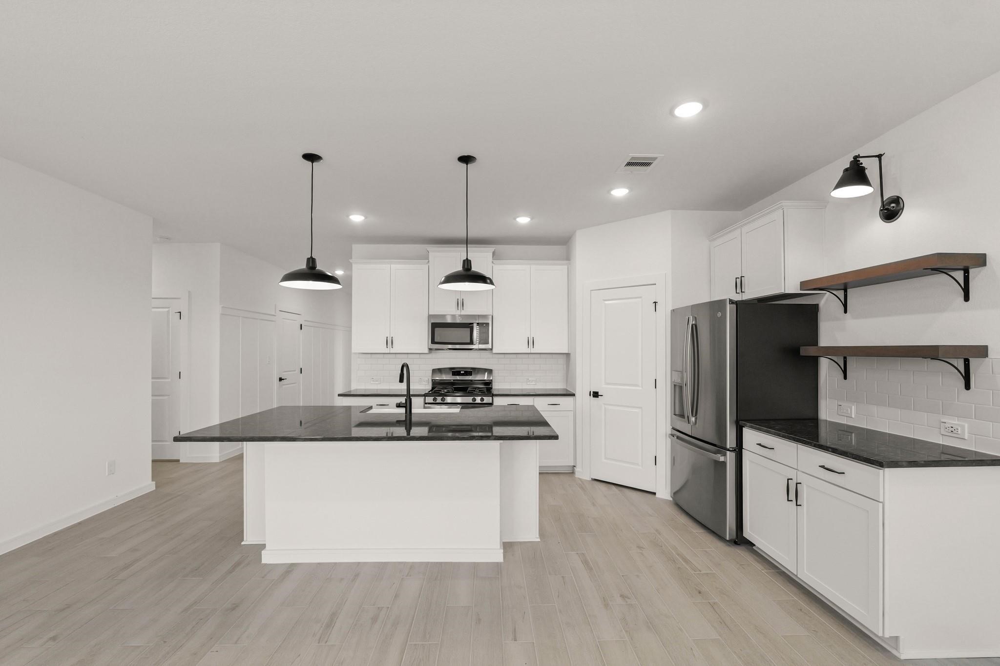 7815 Jade Crest Drive Angleton, TX 77515 - Photo 6 of 31 a large kitchen with stainless steel appliances kitchen island a large counter top and wooden floors