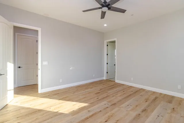 an empty room with a ceiling fan and wooden floor