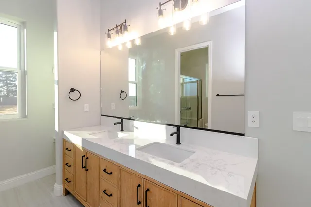 a bathroom with a granite countertop double vanity sink and a mirror