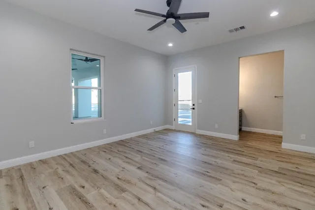 a view of empty room with wooden floor and fan