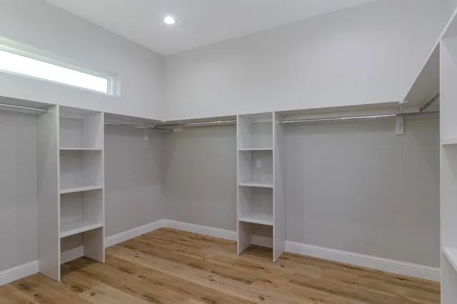 a view of an empty room with wooden floor and closet