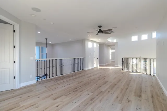 an empty room with wooden floor and a ceiling fan
