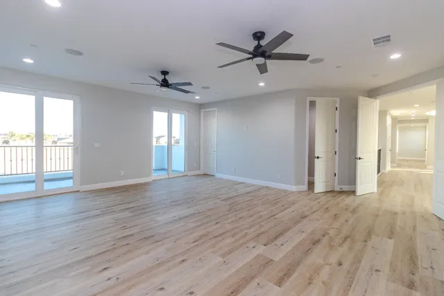 an empty room with wooden floor and a ceiling fan