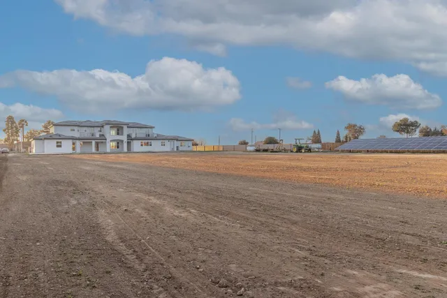 a view of house with a big yard and large trees