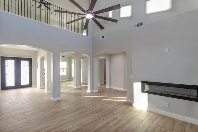 a view of an empty room with wooden floor and a ceiling fan