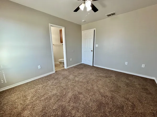 an empty room with a ceiling fan and carpet