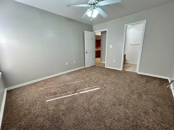 an empty room with closet and a chandelier fan