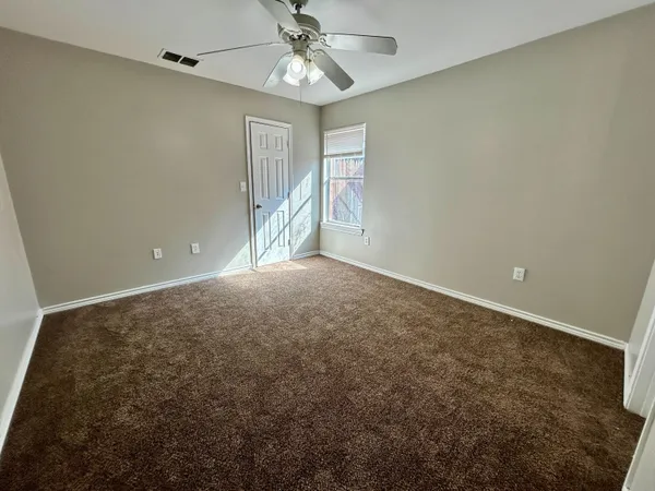 an empty room with a ceiling fan and a window