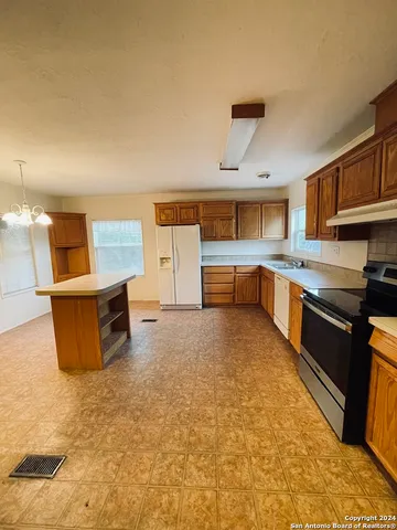 a large kitchen with kitchen island granite countertop a sink and white cabinets