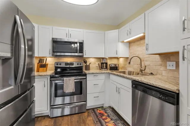 a kitchen with granite countertop a sink stove and refrigerator