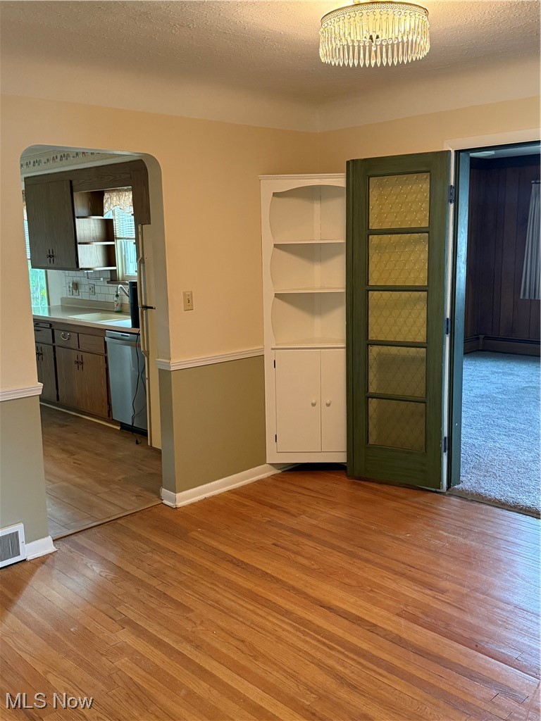 1284 Haverston Road Lyndhurst, OH 44124 - Photo 14 of 43 Empty room with arched walkways, a textured ceiling, light wood-style flooring, and baseboard heating