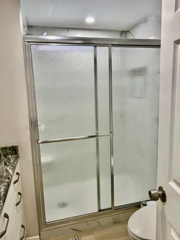 a bathroom with a granite countertop shower and a sink