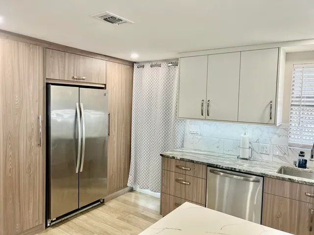 a kitchen with granite countertop a refrigerator sink and cabinets