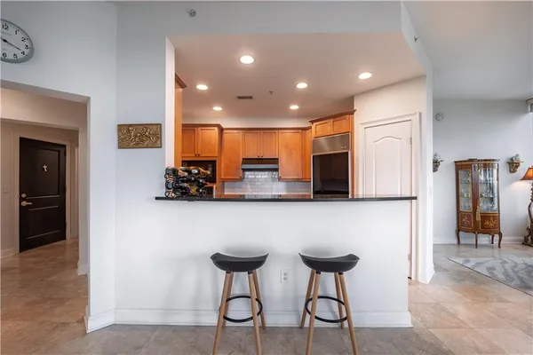 a view of kitchen with stainless steel appliances granite countertop dining table chairs microwave and sink