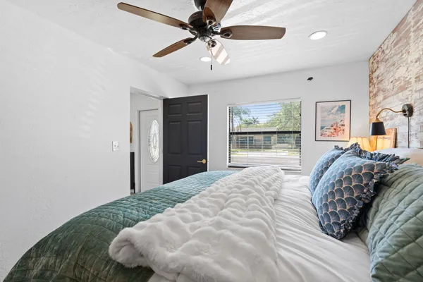 a bed sitting in a bedroom next to a window and a chandelier