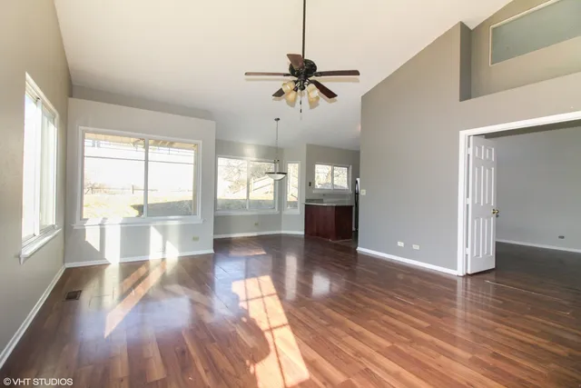 a view of empty room with wooden floor and fan