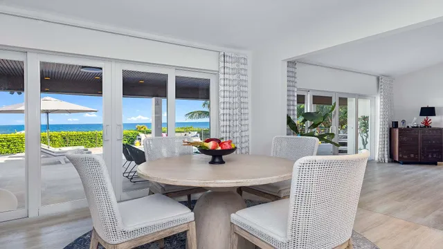 a view of a dining room with furniture a potted plant and a floor to ceiling window