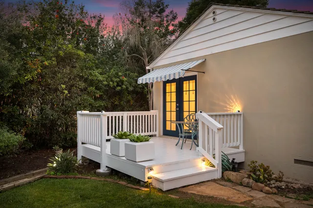 a balcony with table and chairs with wooden fence