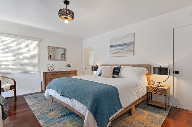 a bedroom with a bed and dresser with wooden floor