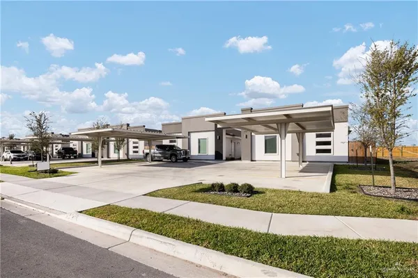 a front view of a house with a yard and potted plants