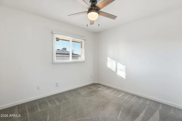 an empty room with a window and a fan