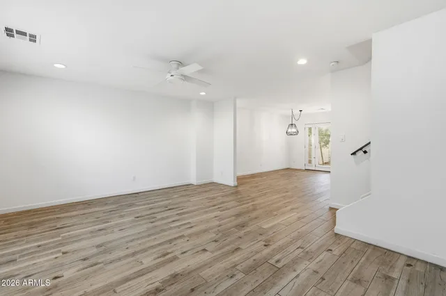 an empty room with wooden floor and windows