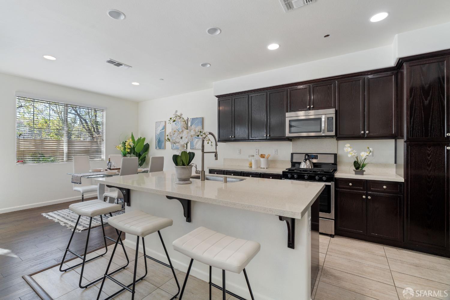 324 MacArthur Way Brentwood, CA 94513 - Photo 10 of 45 a kitchen with kitchen island granite countertop wooden cabinets a stove a microwave a island with a dining table and chairs