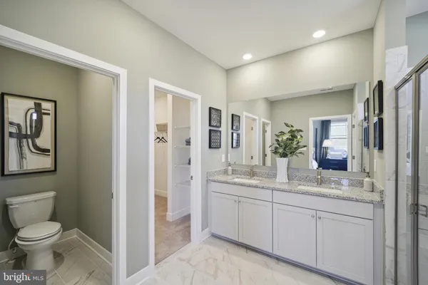 a bathroom with a toilet sink double vanity and mirror
