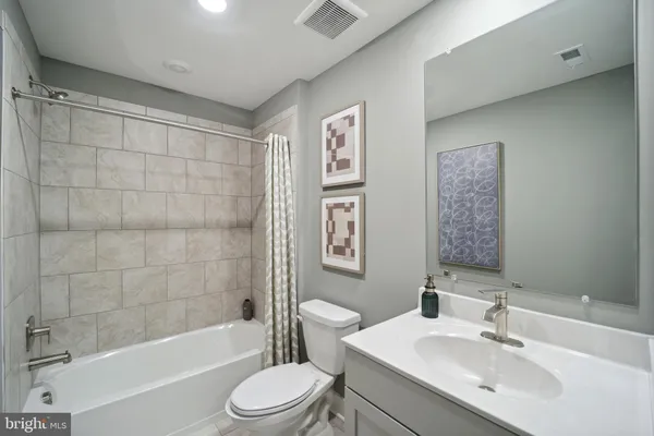 a bathroom with a bathtub shower sink mirror vanity and toilet