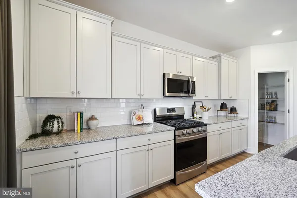 a kitchen with granite countertop white cabinets and stainless steel appliances
