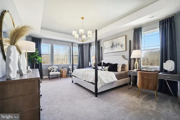 a spacious bedroom with a bed couch chandelier windows and painting on the wall