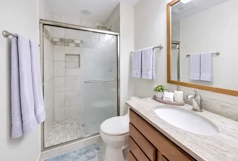 a bathroom with a granite countertop sink toilet and shower