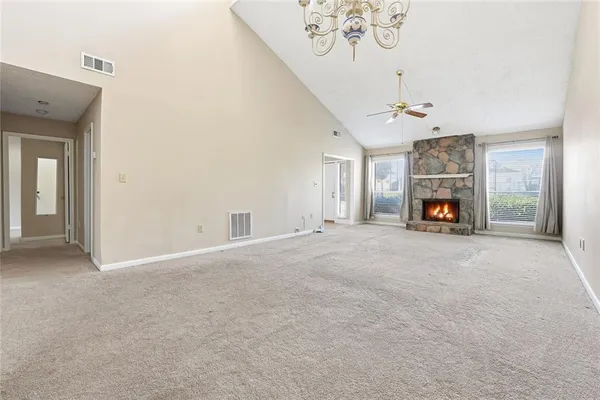 a view of a livingroom with a fireplace a chandelier and windows
