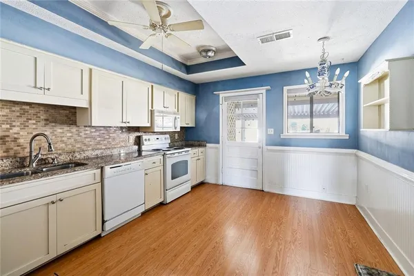 a kitchen with granite countertop wooden floors white cabinets and window