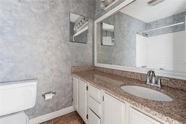 a bathroom with a granite countertop sink a toilet and a mirror