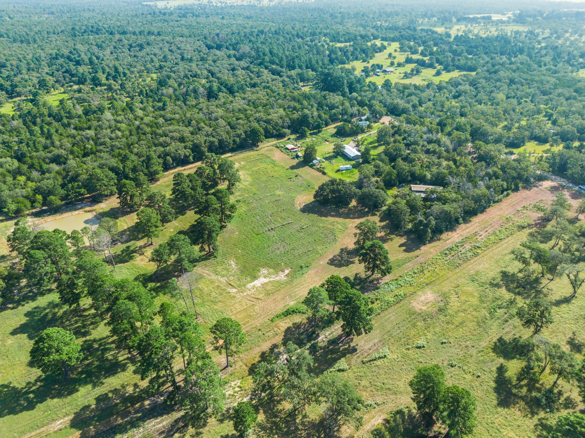170 Split Oak Road Smithville, TX 78957 - Photo 30 of 31 An aerial perspective reveals a sprawling natural landscape with woodlands, open fields, and a serene pond.