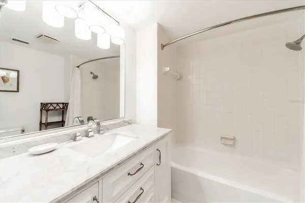 a bathroom with a granite countertop sink a mirror a shower and a bathtub