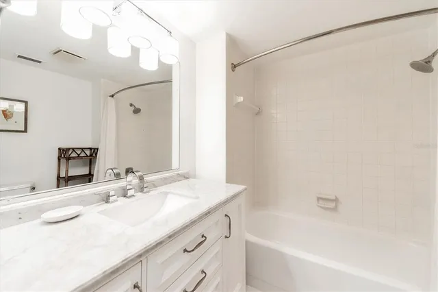 a bathroom with a granite countertop sink a mirror a shower and a bathtub
