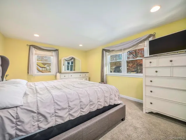 a bedroom with a bed a dresser and flat screen tv
