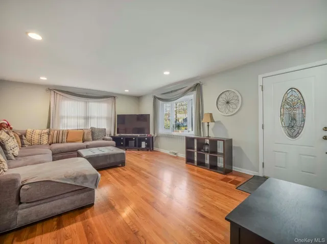 a living room with furniture a clock on wall and a window