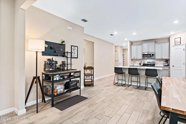 a kitchen with stainless steel appliances kitchen island granite countertop a stove a refrigerator and a dining table with wooden floor