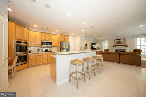 a kitchen with stainless steel appliances kitchen island granite countertop a stove top oven a sink a dining table and chairs