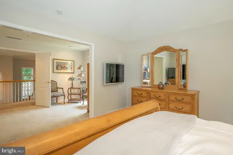 a bedroom with a bed and a large mirror on the dresser