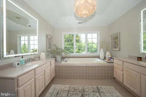 a bathroom with a tub a sink a mirror and a window