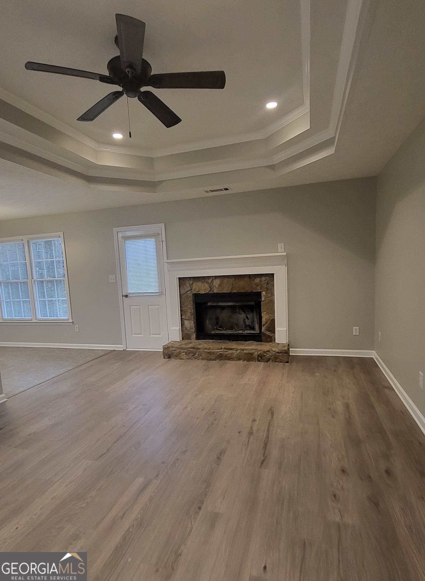 112 Sundown Drive Dawsonville, GA 30534 - Photo 4 of 25 an empty room with wooden floor a ceiling fan and a fireplace